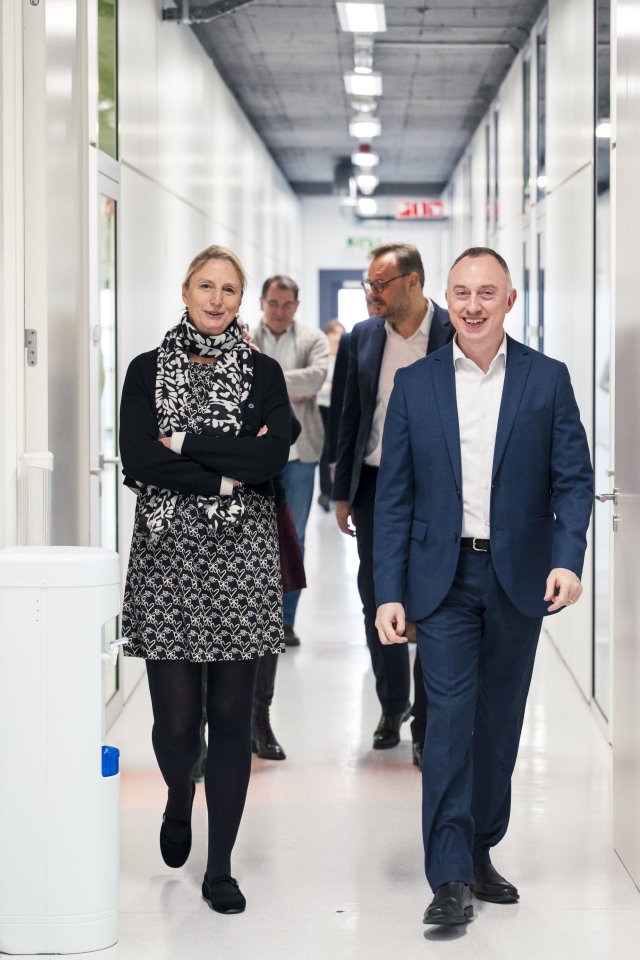 La rectrice de l&rsquo;UCLouvain et le CEO du BLSI marchent dans un couloir, accompagn&eacute;s de plusieurs collaborateurs