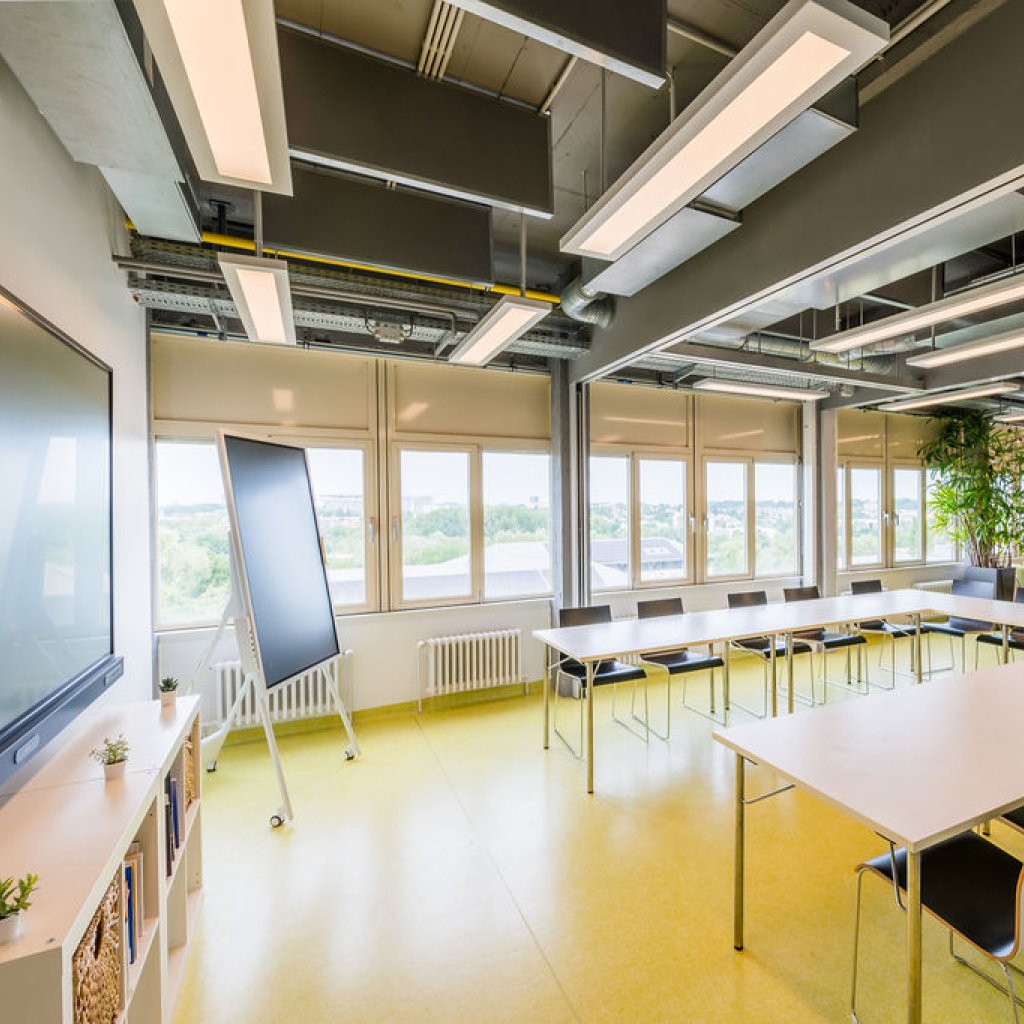 Salle de conf&eacute;rence du BLSI am&eacute;nag&eacute;e en U, pouvant accueillir jusqu&rsquo;&agrave; 35 personnes, avec un &eacute;cran interactif de 86 pouces, un tableau num&eacute;rique de 55 pouces et un espace d&eacute;tente au fond de la salle